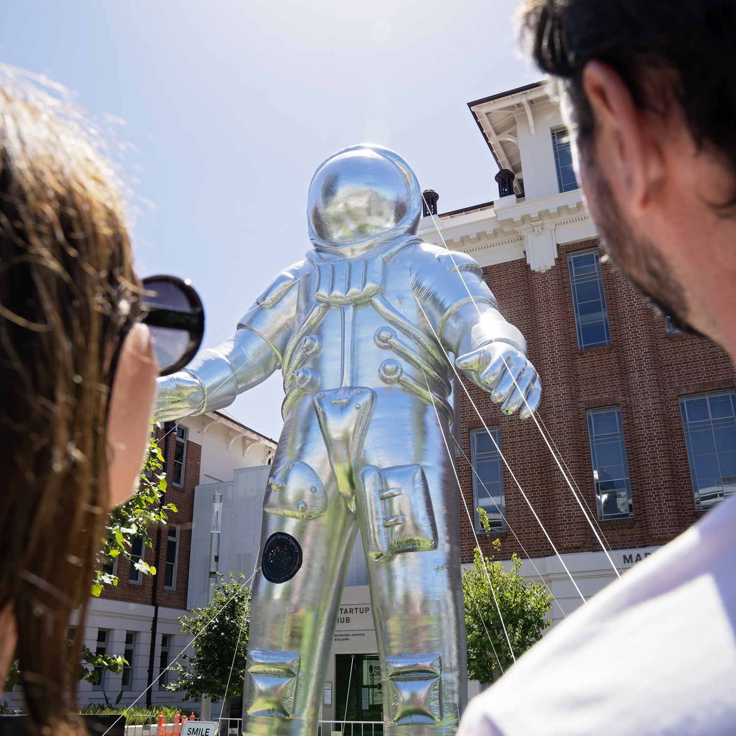 two people posing for a photo in front of a giant inflatable astronaut 