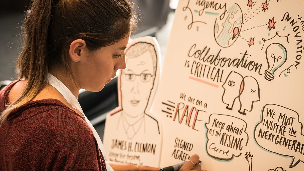 An artist creatively scribing notes from a session. Her sketches reveal a focus on the next STEM generation workforce.