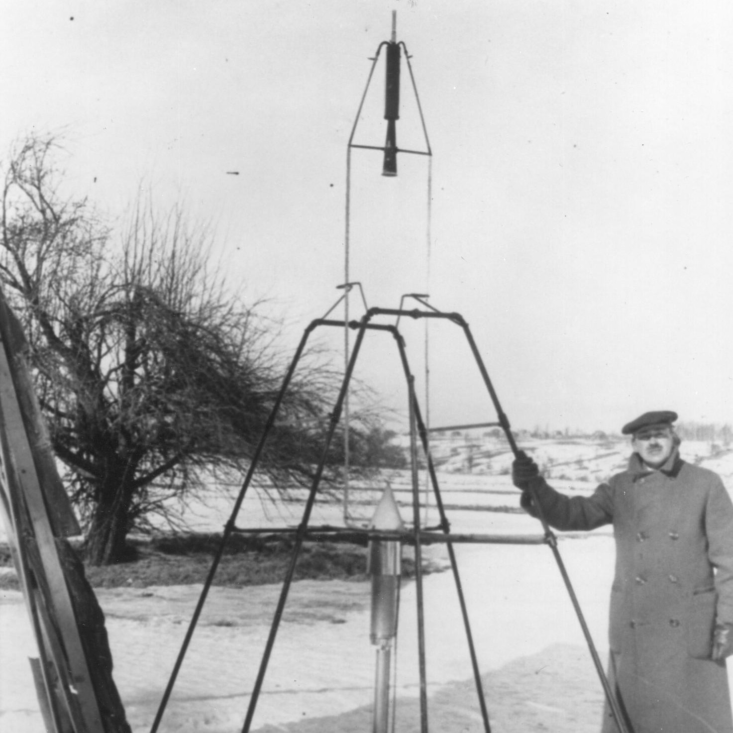 Dr. Robert H. Goddard and a liquid oxygen-gasoline rocket in the frame from which it was fired on March 16, 1926, at Auburn, Massachusetts.