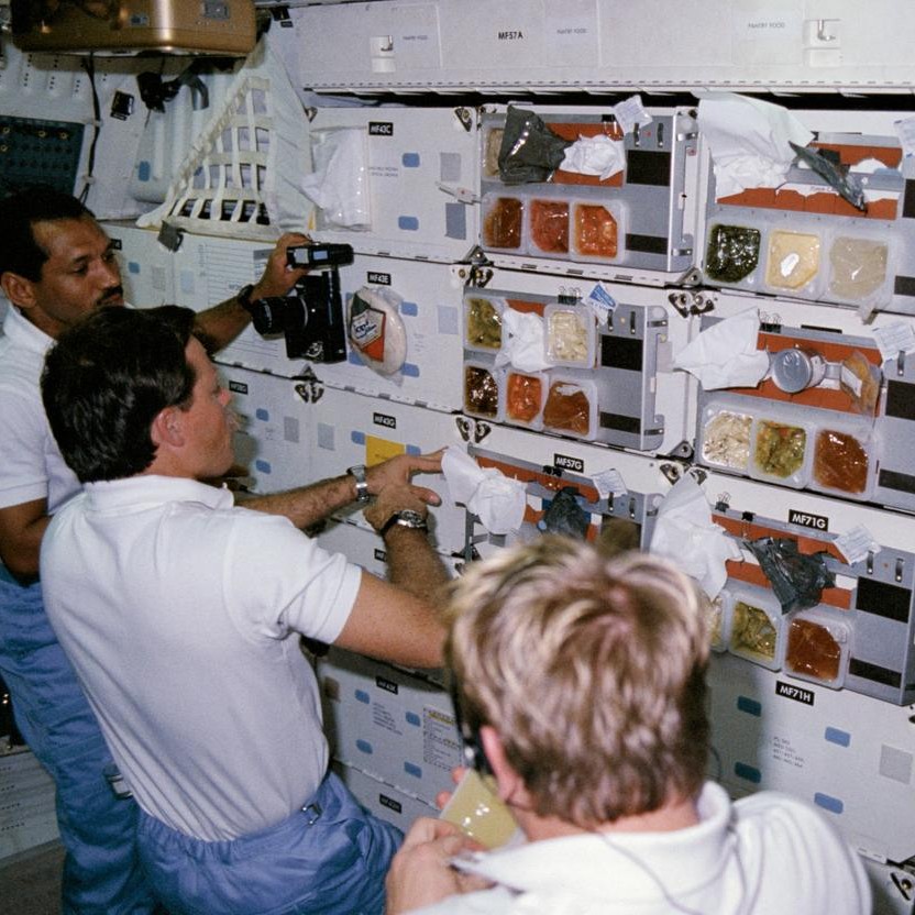 Astronauts queuing at "chow line" on middeck of the space shuttle Columbia. 