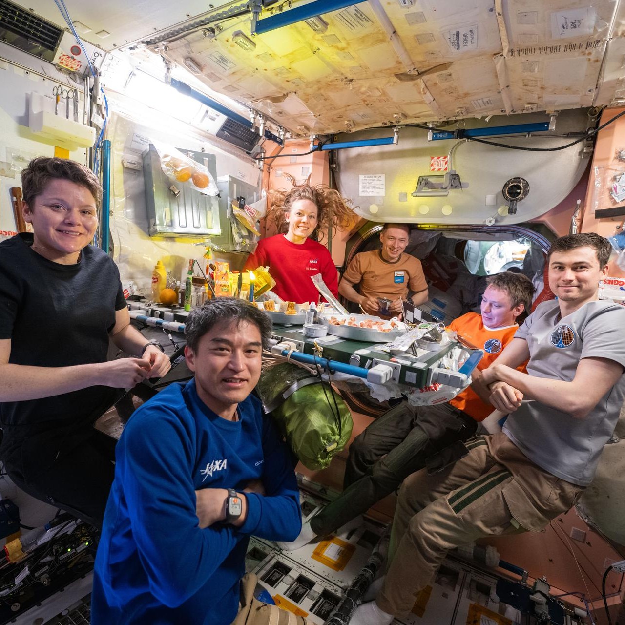 ISS Expedition 73 crewmembers gather around the table for dinner in NASA’s Unity module.