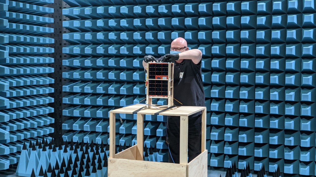 DSTG Engineer Darin Roberts attaches a radio frequency cable to the engineering model spacecraft during anechoic chamber testing at REDARC Defence & Space