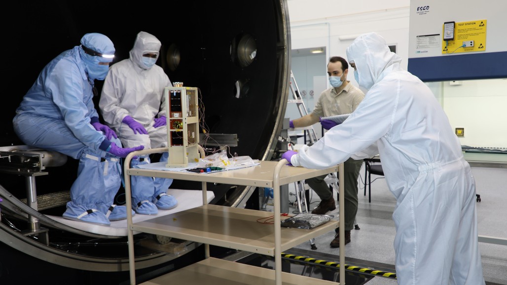 DSTG Engineers Vidul Malavde, Harrison Bennett and Paul Alvino, and head of National Space Test Facility, Eduardo Trifoni, prepare the flight model spacecraft for thermal vacuum testing.