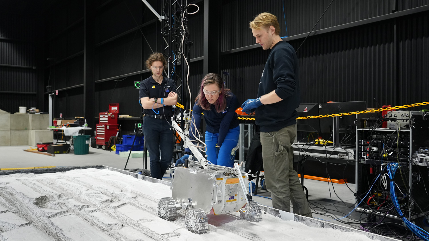 The ATCSR team observing the Roo-ver prototype in the regolith pit.