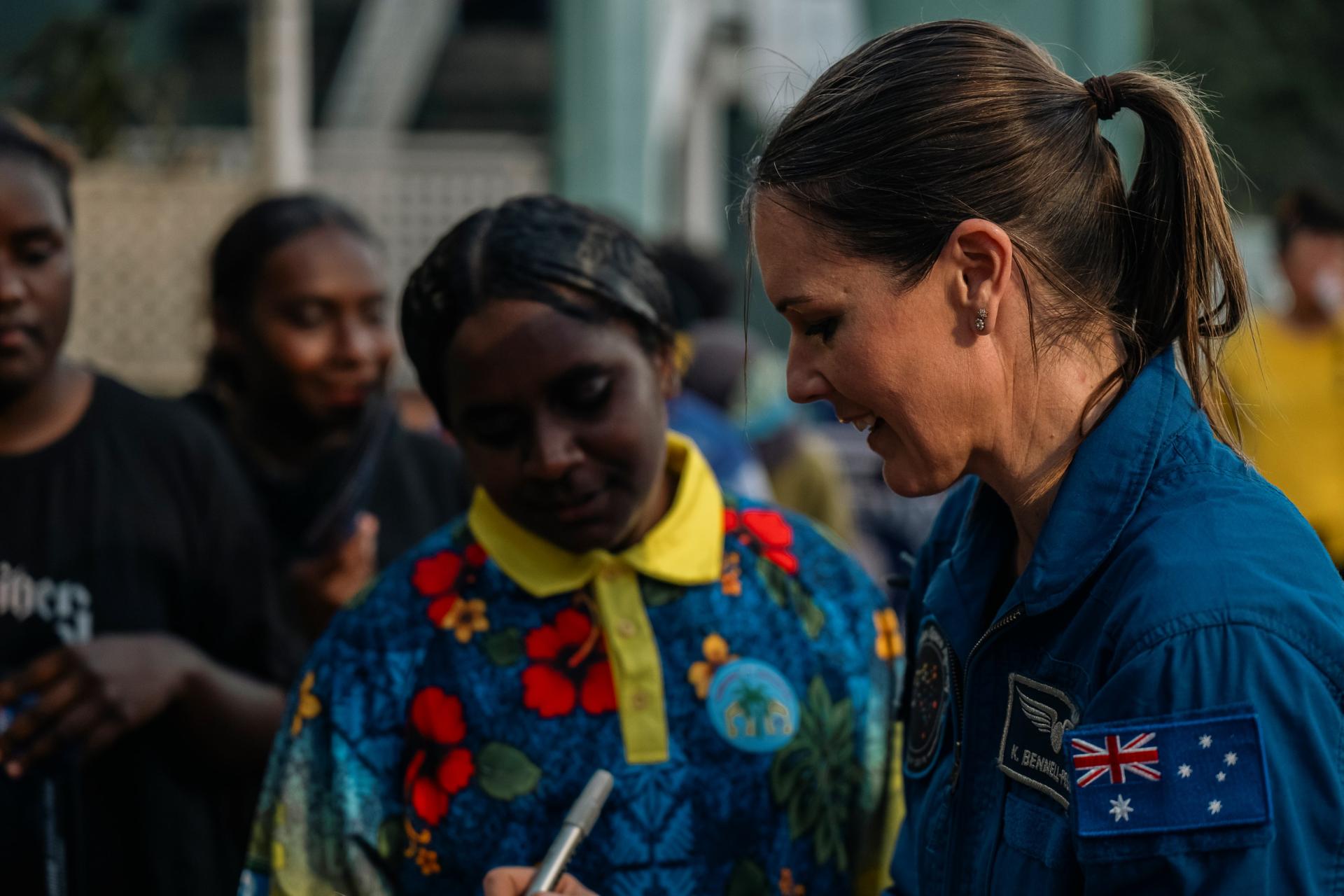 Aussie astronaut Katherine Bennell-Pegg signing a postcard for young space enthusiasts from the Torres Strait