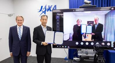 Presentation of signed agreement between Australia and Japan. Two men standing beside a tv screen, with two people featured on the screen