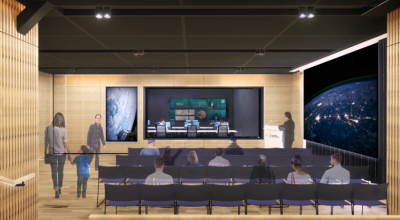 An artist impression of mission control shows a theatrette with light timber panelling and a dark ceiling. A presenter is standing before people seated in rows of chairs, a man is entering the room, and a woman with a child is leaving it.
