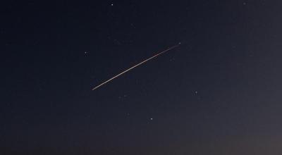 A fireball shoots across a dark sparsely stared sky