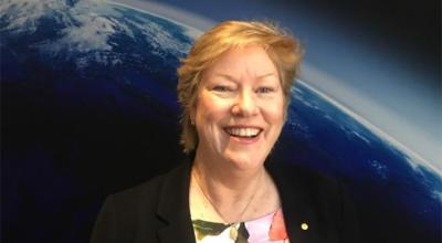 Image of Dr Clark in front of a picture of Earth