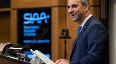 Enrico Palermo at a lectern holding his speech and smiling at the audience. The Space Industry Association of Australia’s (SIAA) logo is on a digital board in the background.
