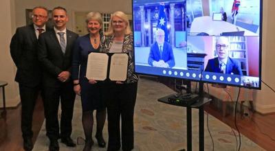 Displaying of the signed document between Australia and the uk with some participants appearing on an screen