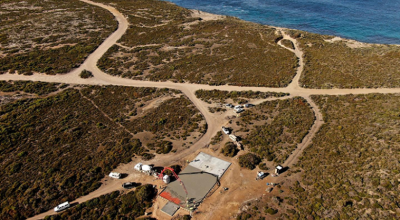 Birds-eye view of a rocket launch platform under construction and surrounding bush land by the sea.