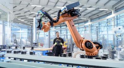 Man in factory working with large hi-tech robotics machine.