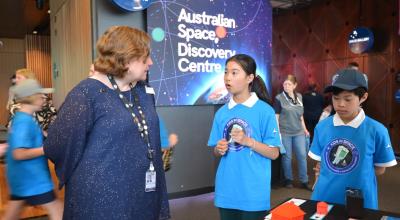 Young students and an adult standing next to a design concept.