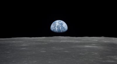 View from the Apollo 11 spacecraft shows the Earth and Australia rising above the Moon's horizon. The lunar terrain pictured is in the area of Smyths Sea on the nearside.