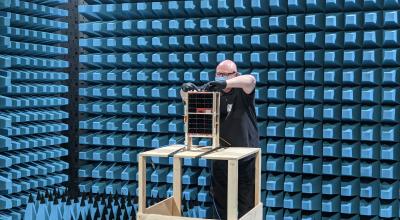 DSTG Engineer Darin Roberts attaches a radio frequency cable to the engineering model spacecraft during anechoic chamber testing at REDARC Defence & Space.