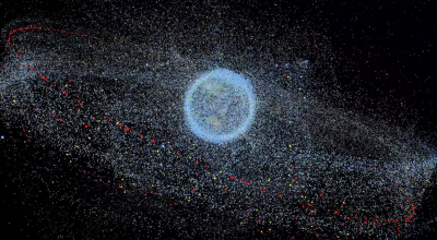 An image of the Earth appears on a black background. The Earth is swarmed by satellites and space debris that form a glowing, granular cloud around it.