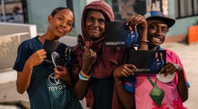 Young Torres Straight islanders holding signed postcards of Katherine