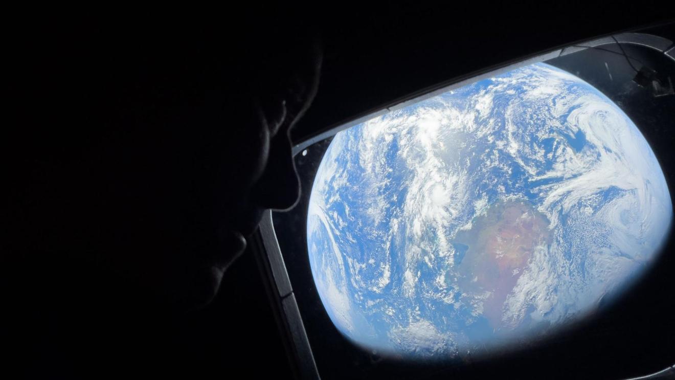 NASA astronaut and Artemis II Commander Reid Wiseman peers out of one of the Orion spacecraft's main cabin windows, looking back at Earth, as the crew travels towards the Moon.  Image Credit: NASA