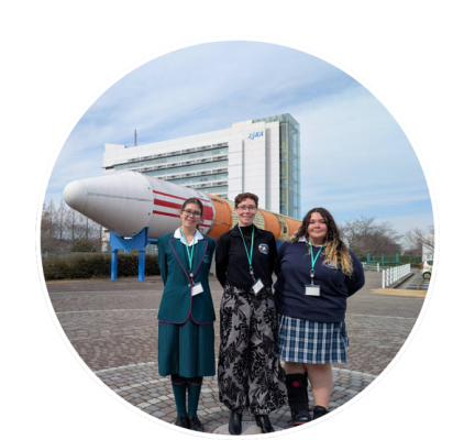 A group photo in front of a Japanese rocket model