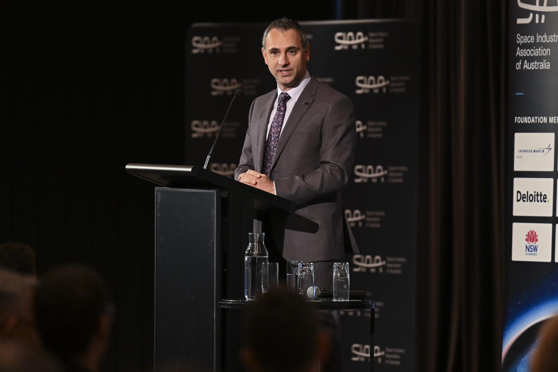 Person in formal attire talking from an event's stage. 