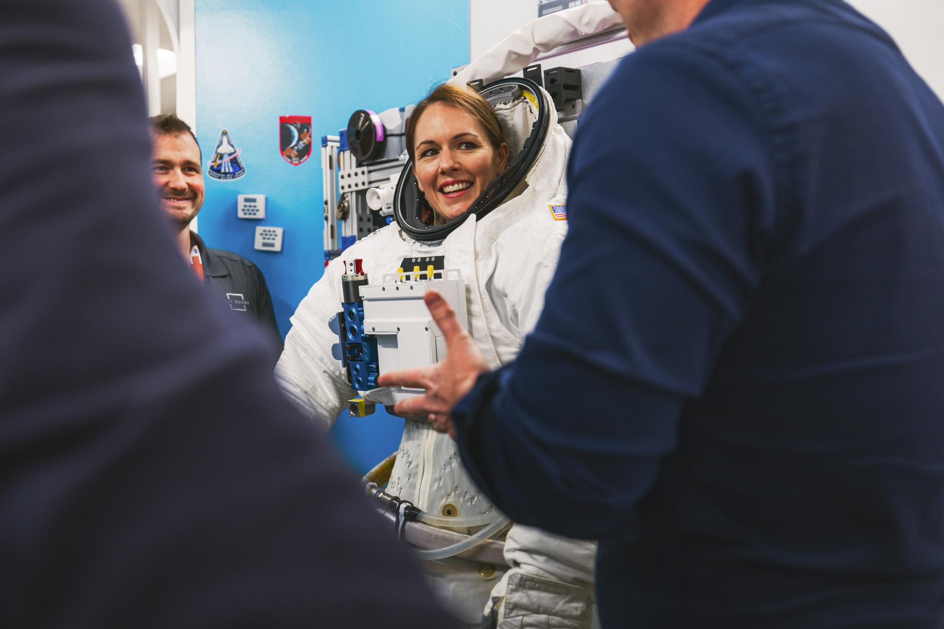 A woman in an astronaut suit smiling.