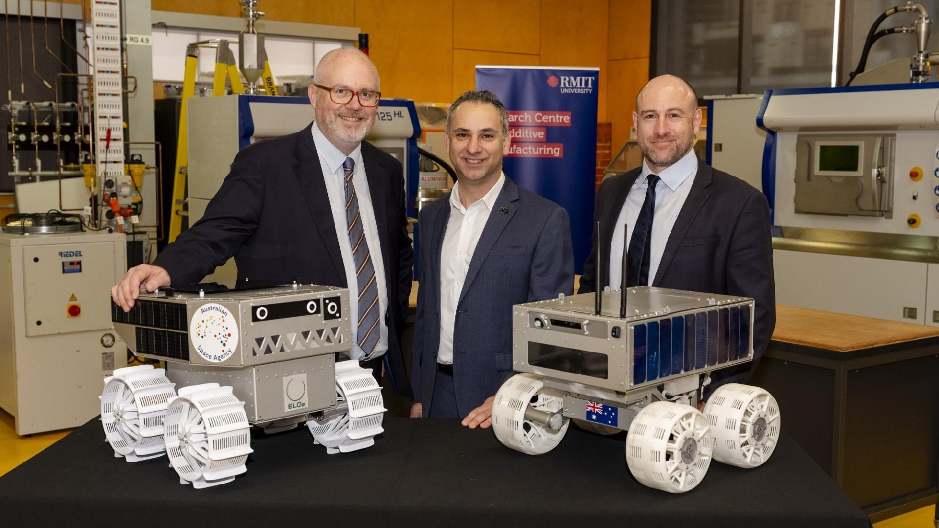 Minister for Industry and Innovation and Minister for Science Tim Ayres along with Head of the Australian Space Agency Enrico Palermo and ELO2 consortium director Ben Sorenson. They are standing in front of two prototypes of Australia's lunar rover.