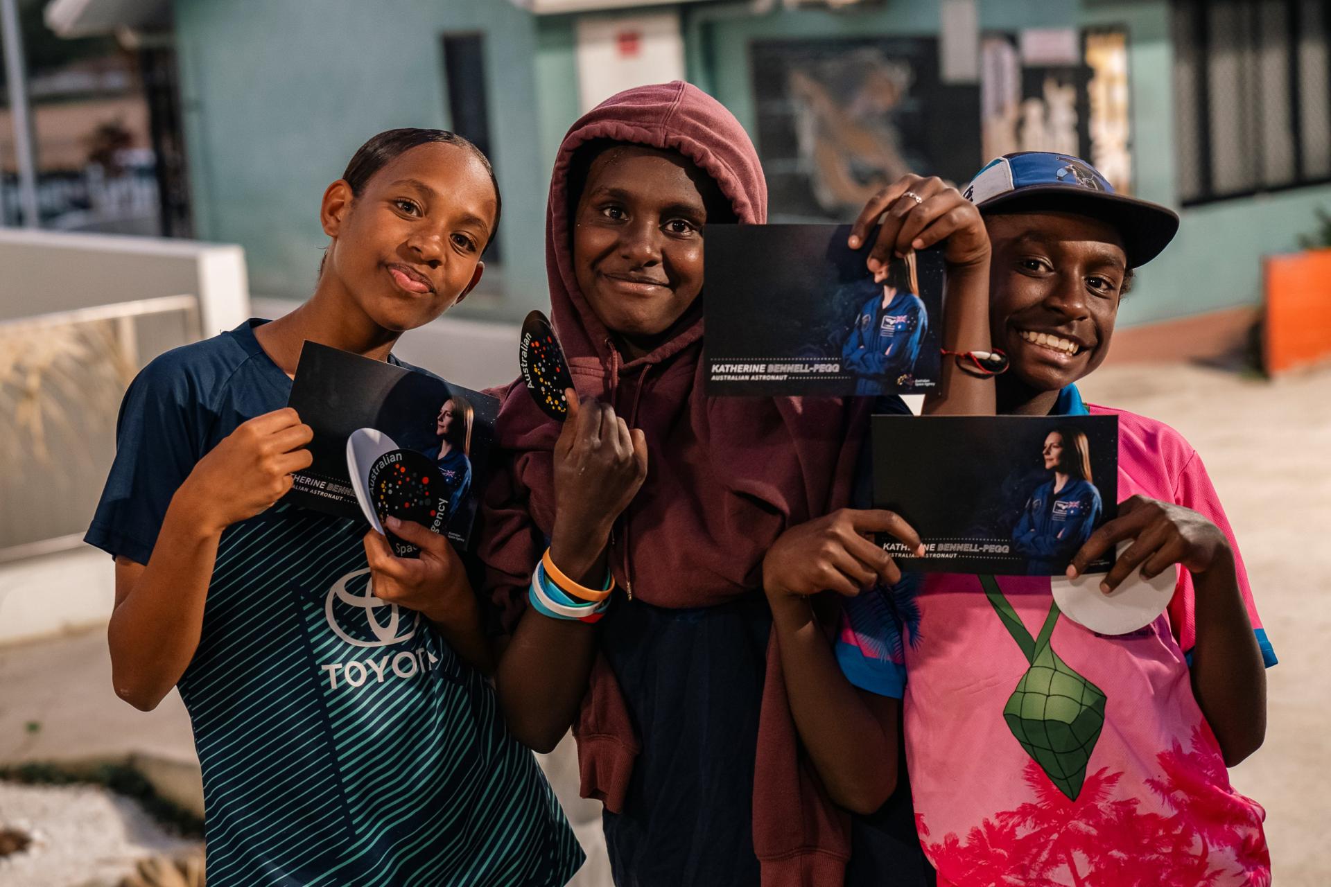 Young Torres Straight islanders holding signed postcards of Katherine